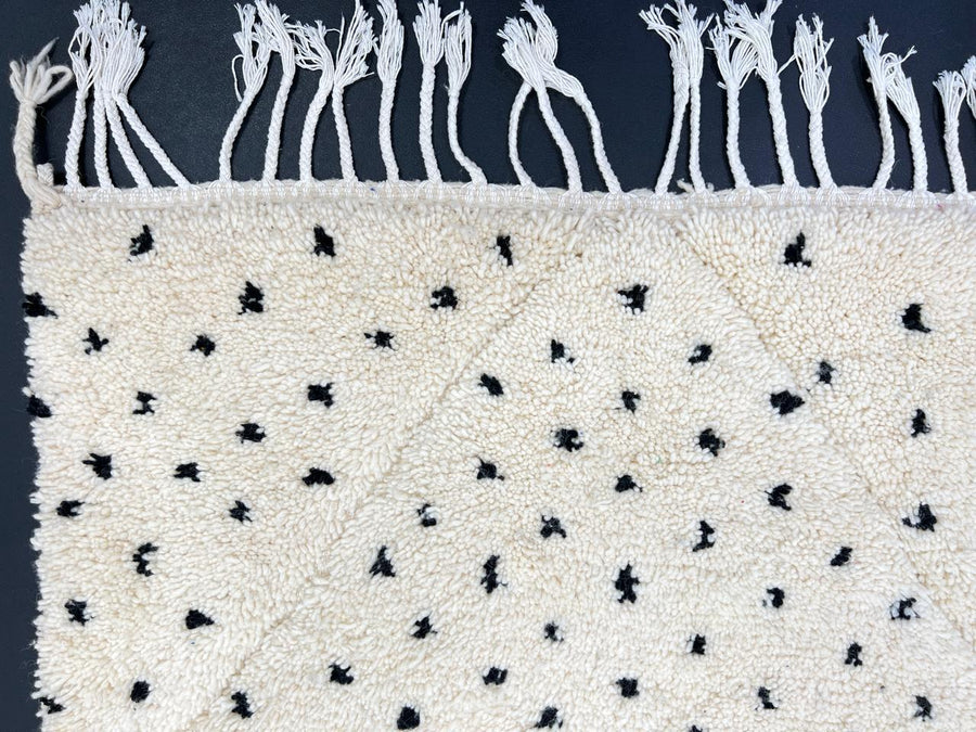Handmade Moroccan runner rug with black dotted tuft pattern and soft geometric diamond outlines on a white wool background.