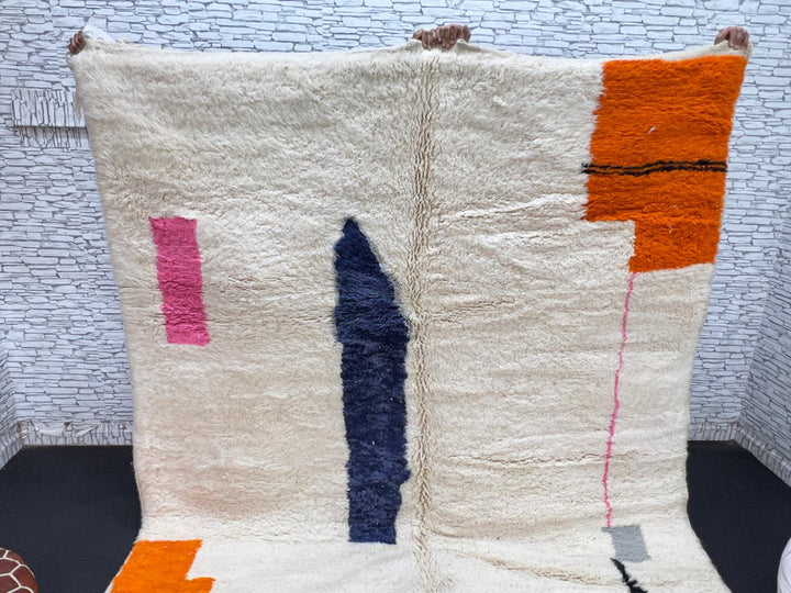 Minimalist Moroccan wool rug with abstract navy, orange and pink line design on cream background