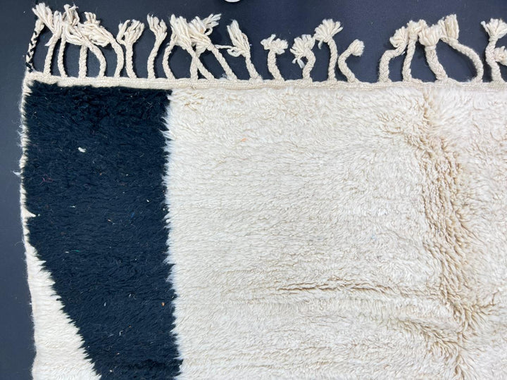Minimalist Moroccan wool rug with abstract navy, orange and pink line design on cream background
