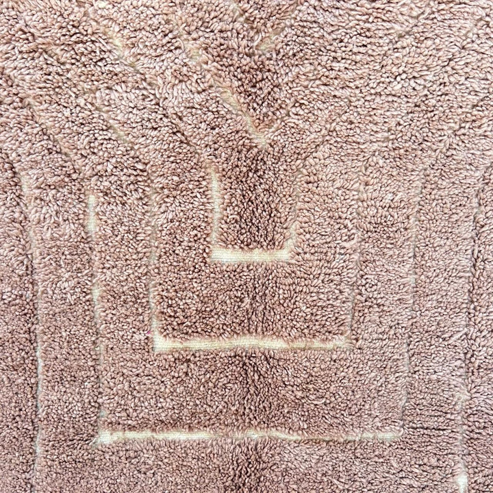 Authentic round Moroccan Berber rug handmade from natural wool with traditional tribal motif in warm beige tones