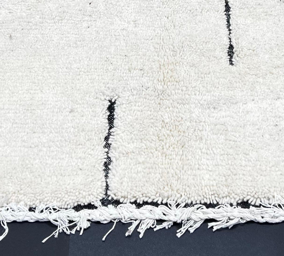 Handmade minimalist Moroccan runner rug with black linear abstract design on natural white wool background.