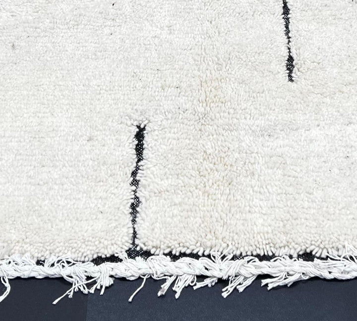 Handmade minimalist Moroccan runner rug with black linear abstract design on natural white wool background.