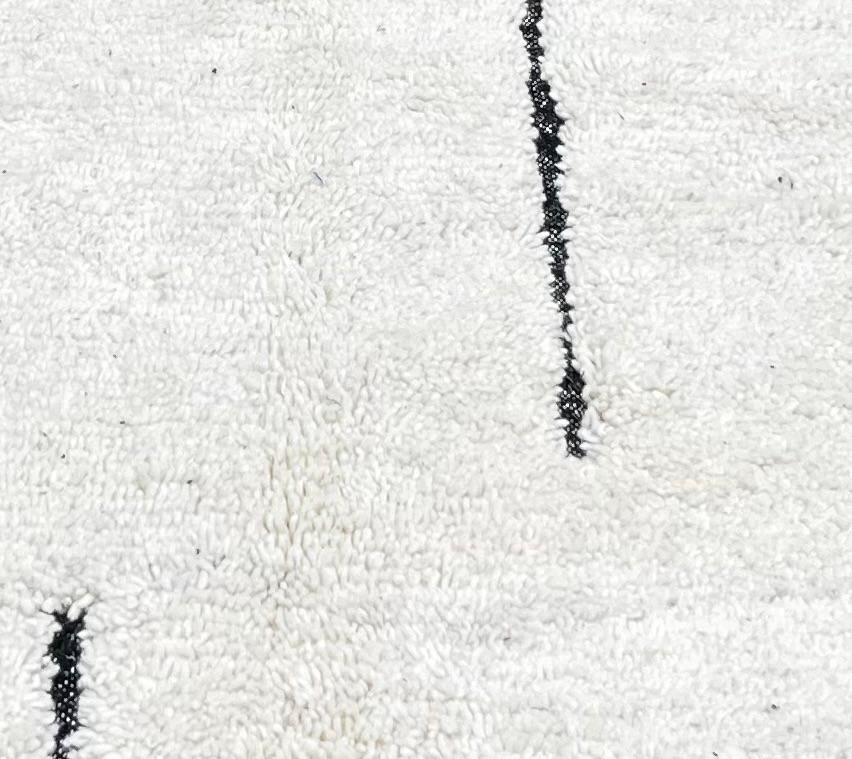 Handmade minimalist Moroccan runner rug with black linear abstract design on natural white wool background.