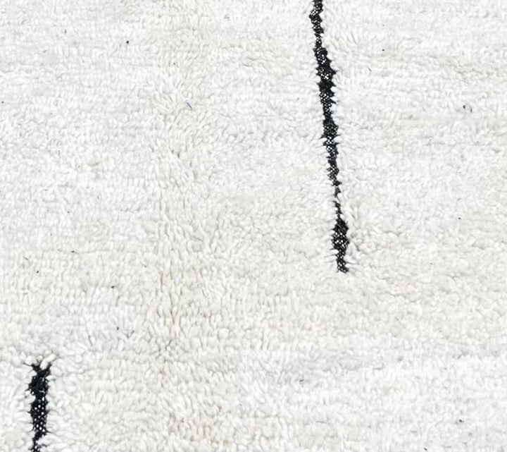 Handmade minimalist Moroccan runner rug with black linear abstract design on natural white wool background.
