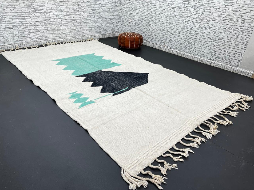 Handwoven Moroccan flatweave wool rug with mint green and black geometric design on ivory background