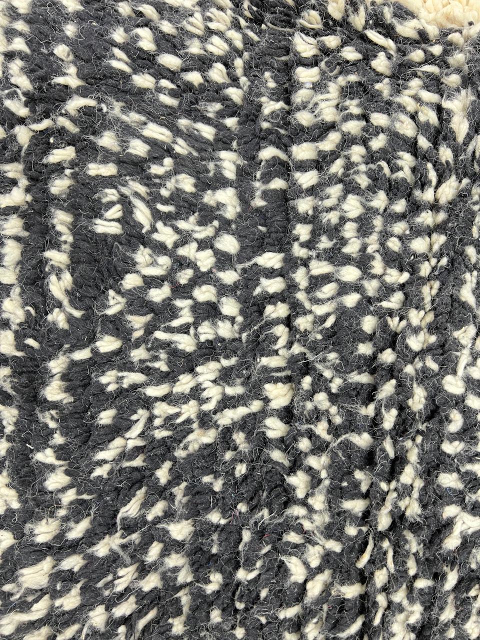 Round modern Moroccan rug with abstract black, white, and red textured pattern.