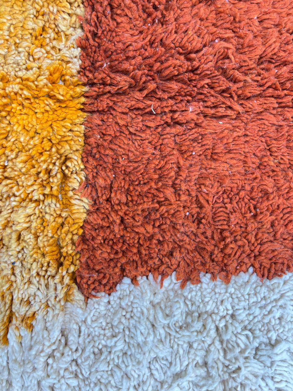 Handmade Moroccan runner rug with colorful abstract geometric shapes in blue, pink, and orange on a white wool background.