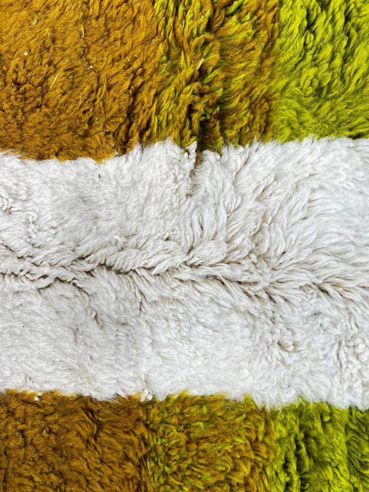 Handmade modern abstract Moroccan wool runner rug with geometric black, green, yellow, and pink design on a white background