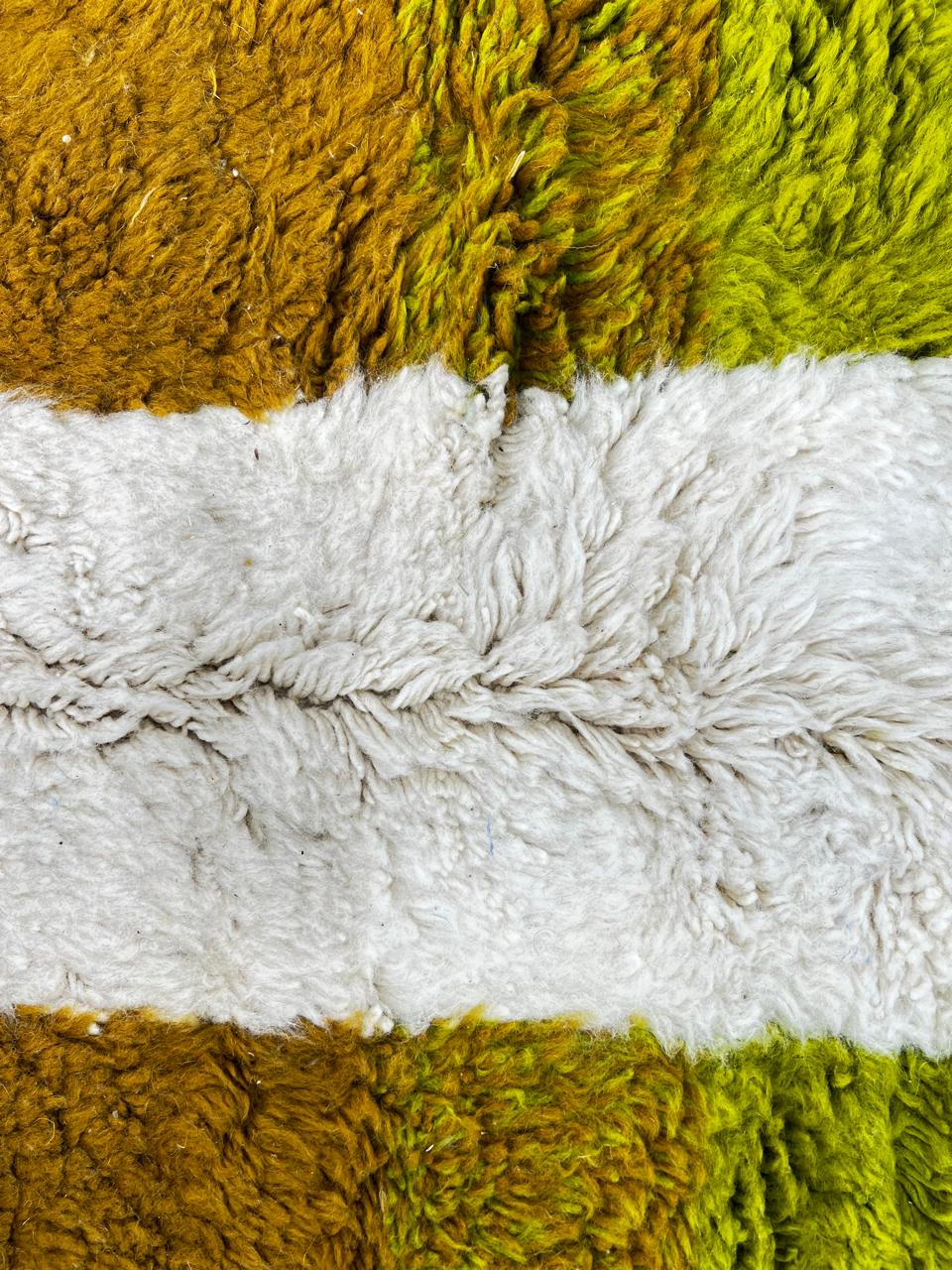 Modern abstract Moroccan wool rug with geometric blocks in black, green, and ochre, handmade by Berber artisans