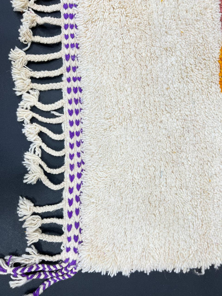 Handmade modern Moroccan wool runner rug with bold abstract geometric shapes in purple, fuchsia, orange, and green on a white background