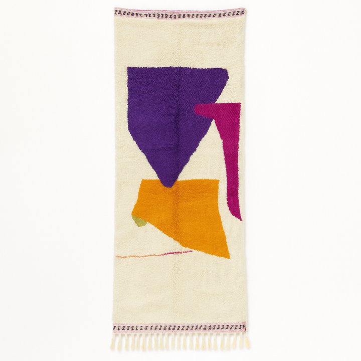 Handmade modern Moroccan wool runner rug with bold abstract geometric shapes in purple, fuchsia, orange, and green on a white background