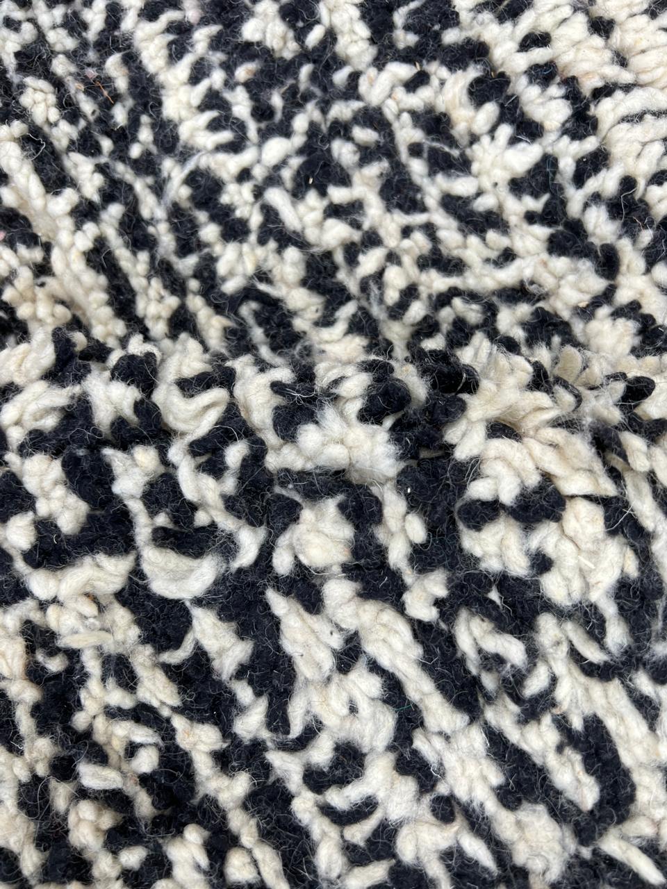 Round modern Moroccan rug with abstract pink, red, black, and white pattern.