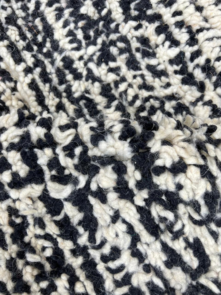 Round modern Moroccan rug with abstract pink, red, black, and white pattern.