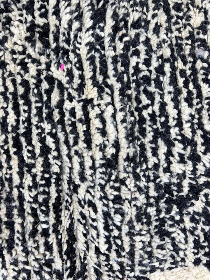 Round modern Moroccan rug with abstract pink, red, black, and white pattern.