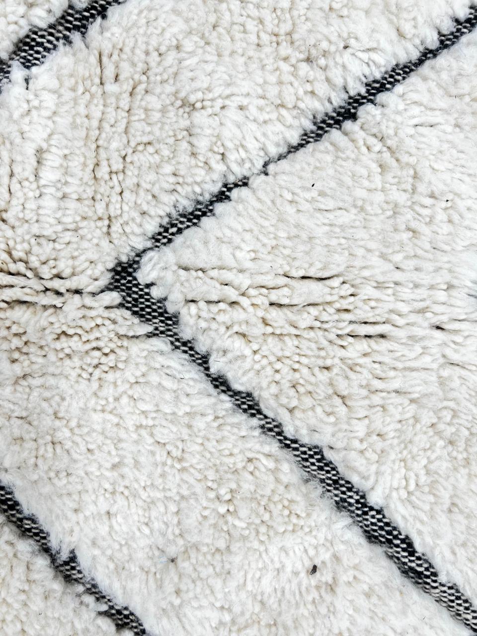 Modern Moroccan Beni Ourain wool rug with black chevron lines on cream background, handmade by Berber artisans