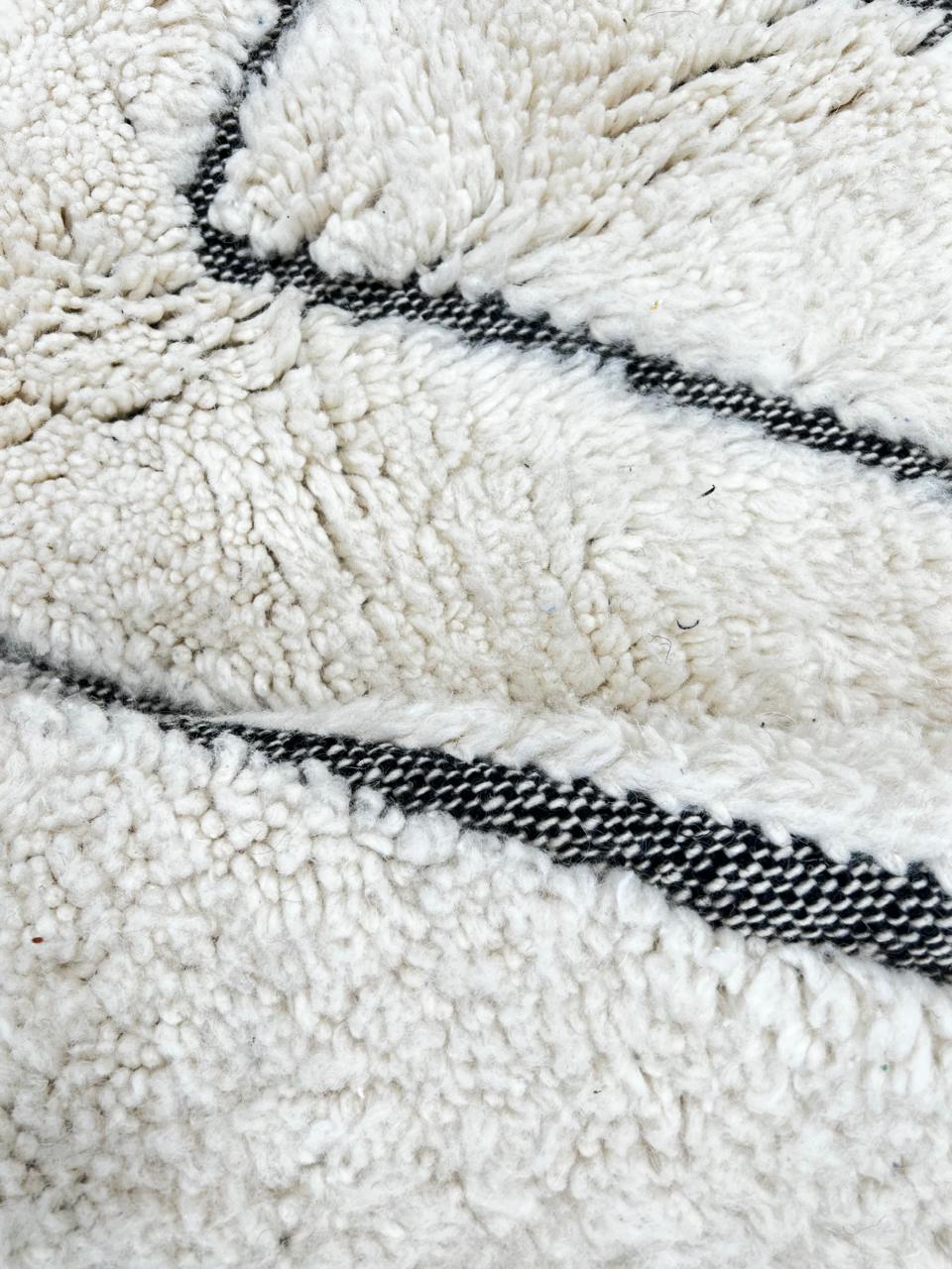 Modern Moroccan Beni Ourain wool rug with black chevron lines on cream background, handmade by Berber artisans