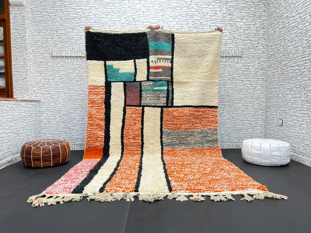 Handmade Moroccan wool rug with geometric color block design in orange, black, teal, and pink tones