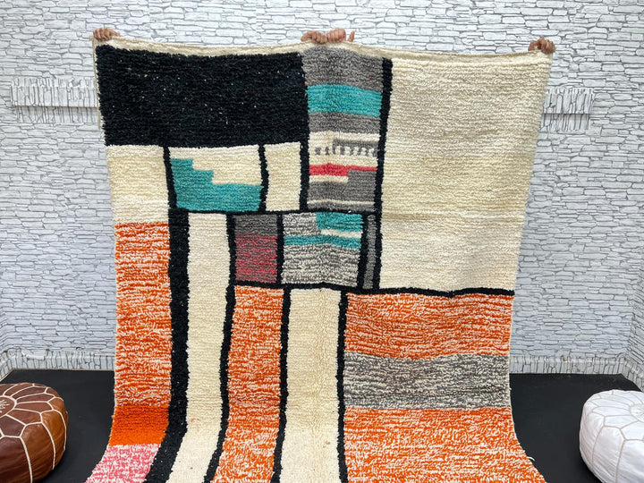 Handmade Moroccan wool rug with geometric color block design in orange, black, teal, and pink tones