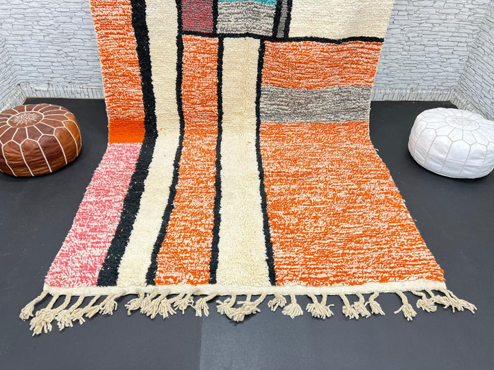 Handmade Moroccan wool rug with geometric color block design in orange, black, teal, and pink tones