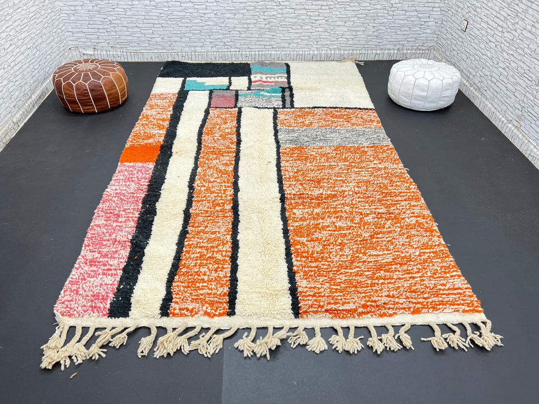 Handmade Moroccan wool rug with geometric color block design in orange, black, teal, and pink tones