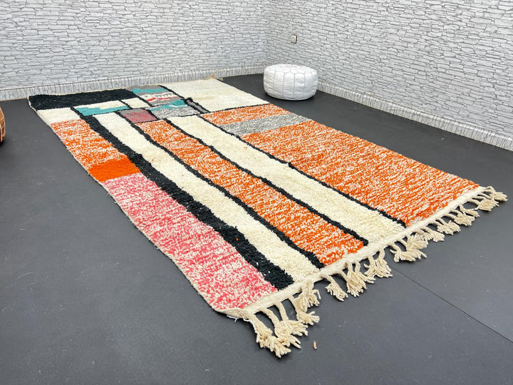 Handmade Moroccan wool rug with geometric color block design in orange, black, teal, and pink tones