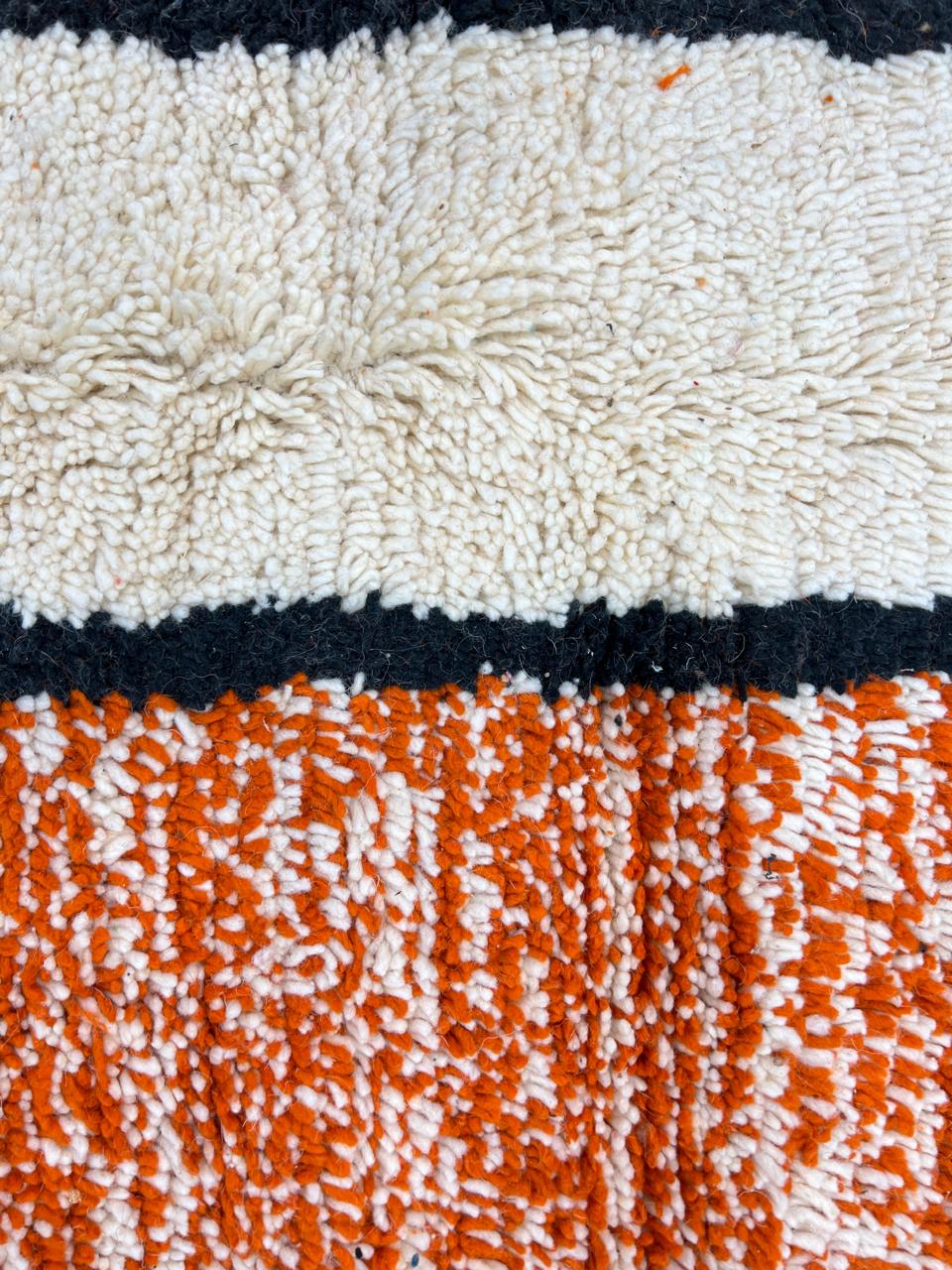 Handmade Moroccan wool rug with geometric color block design in orange, black, teal, and pink tones