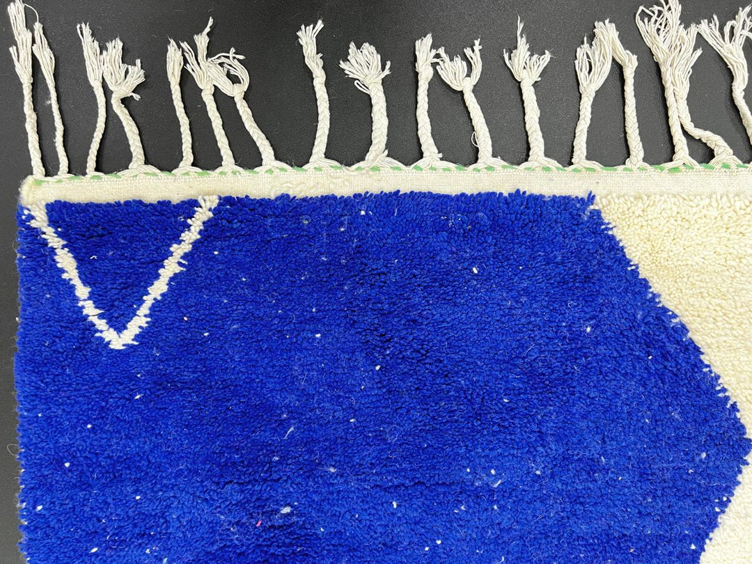 Handmade Moroccan runner rug with geometric blue, green, and black shapes on a white wool background.