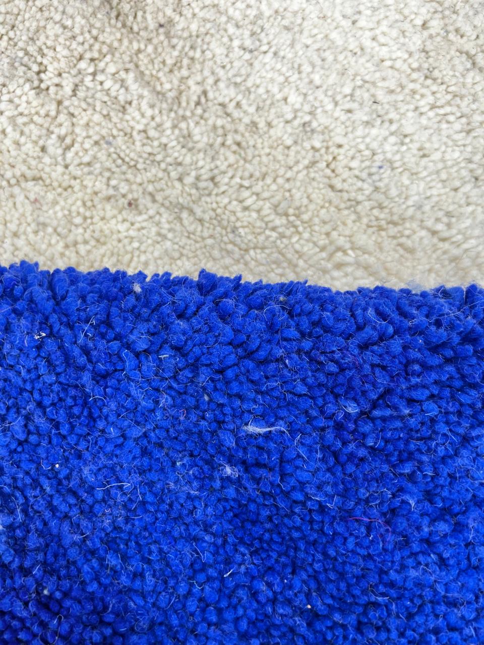 Handmade Moroccan runner rug with geometric blue, green, and black shapes on a white wool background.