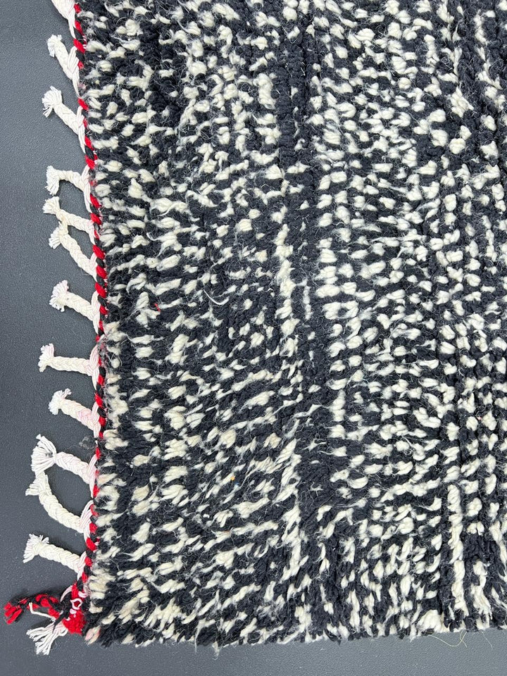 Handmade modern Moroccan runner rug with black, white, and red abstract design, crafted from natural wool by Berber artisans.