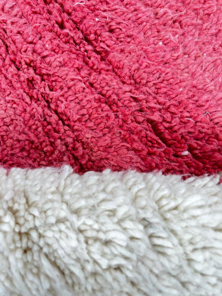 Handmade modern Moroccan wool runner rug with red, burgundy, and pink geometric hourglass design on white background