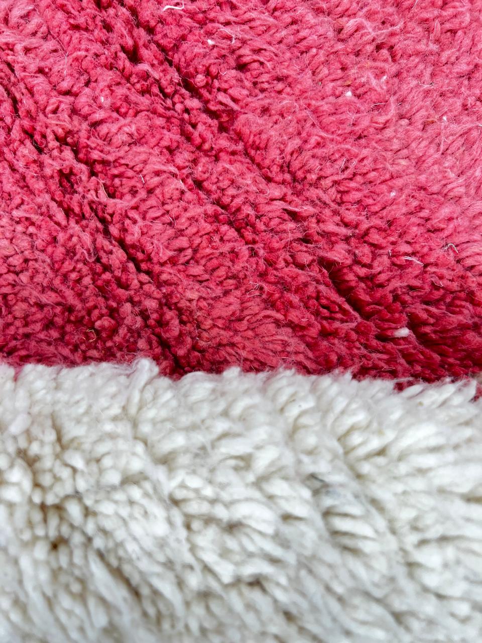 Handmade modern Moroccan wool runner rug with red, burgundy, and pink geometric hourglass design on white background