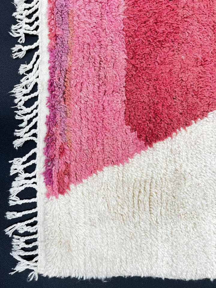 Handmade modern Moroccan wool runner rug with red, burgundy, and pink geometric hourglass design on white background