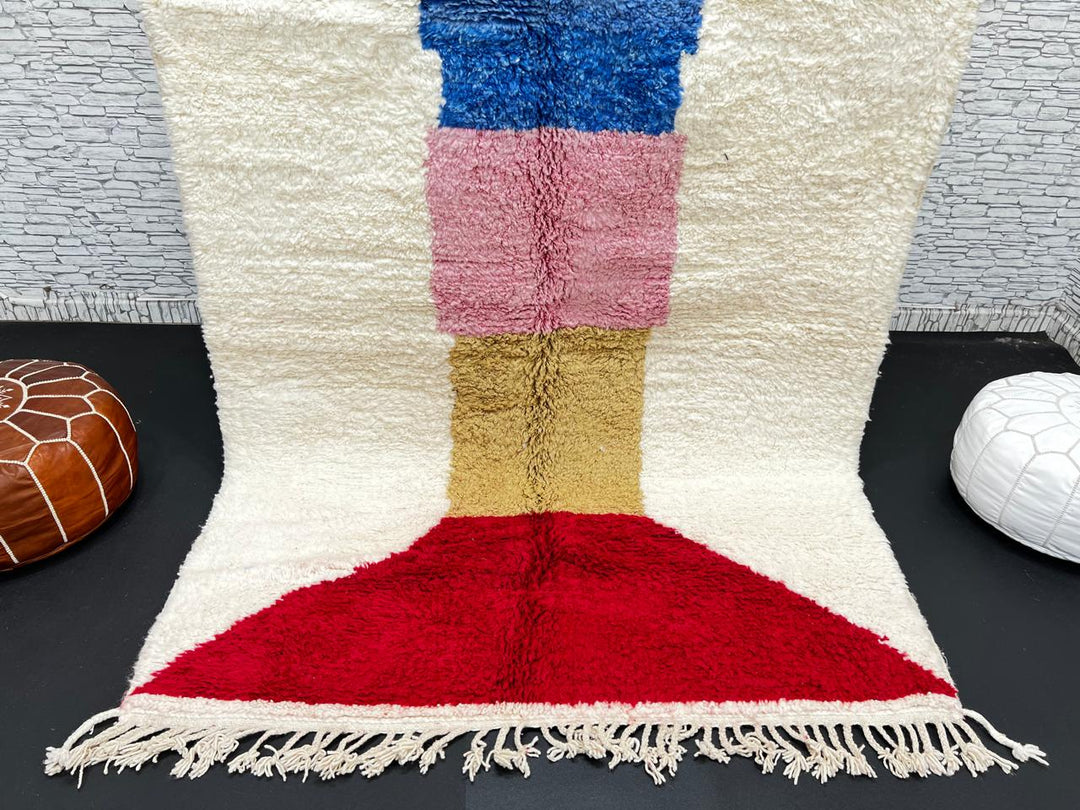 Handwoven Moroccan wool rug with ivory background and colorful geometric blocks in green, blue, pink, mustard, and red