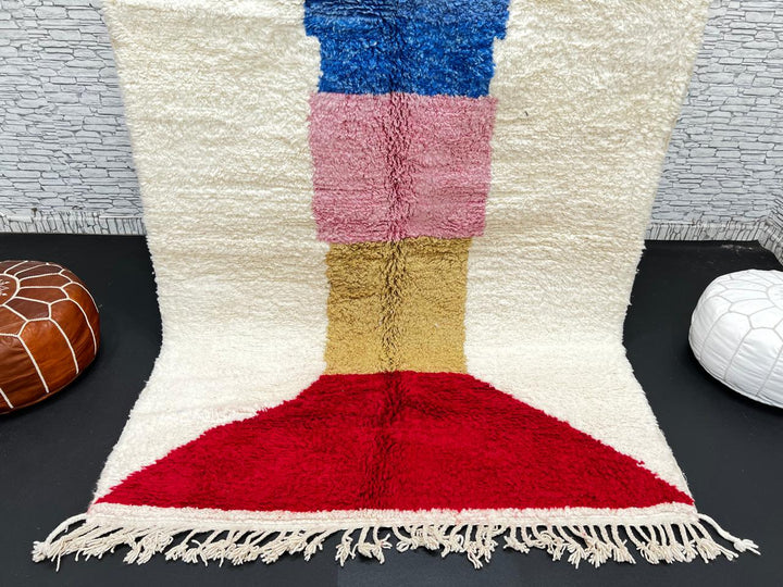 Handwoven Moroccan wool rug with ivory background and colorful geometric blocks in green, blue, pink, mustard, and red