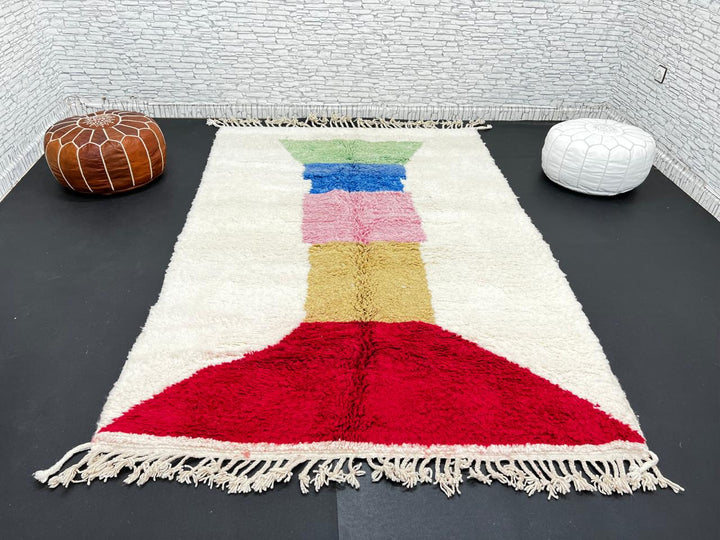 Handwoven Moroccan wool rug with ivory background and colorful geometric blocks in green, blue, pink, mustard, and red