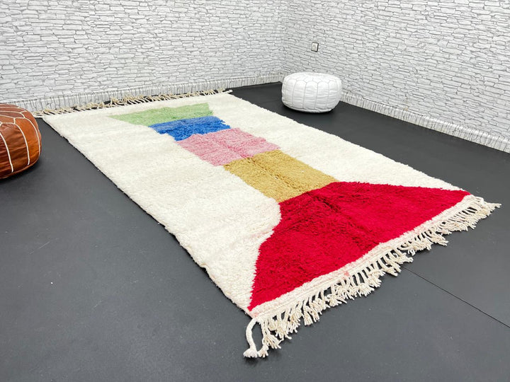Handwoven Moroccan wool rug with ivory background and colorful geometric blocks in green, blue, pink, mustard, and red