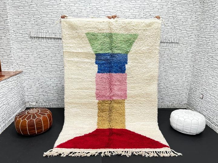Handwoven Moroccan wool rug with ivory background and colorful geometric blocks in green, blue, pink, mustard, and red