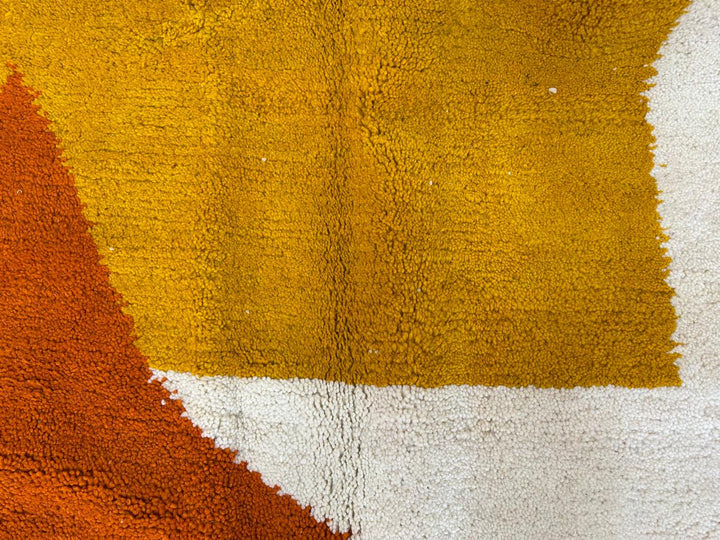Handmade modern Moroccan wool rug in cream with mustard yellow and terracotta geometric Berber design, plush shag texture with tassels