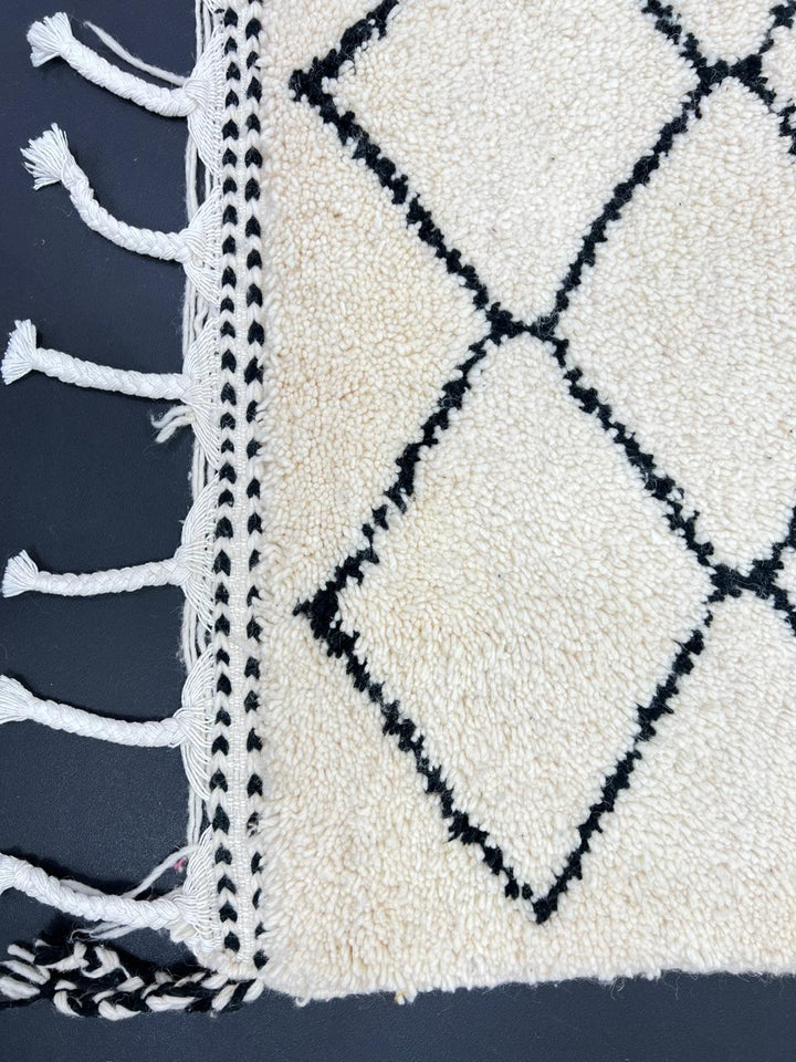 Handmade Moroccan runner rug with classic black diamond lattice design on a white wool background, crafted by Berber artisans.