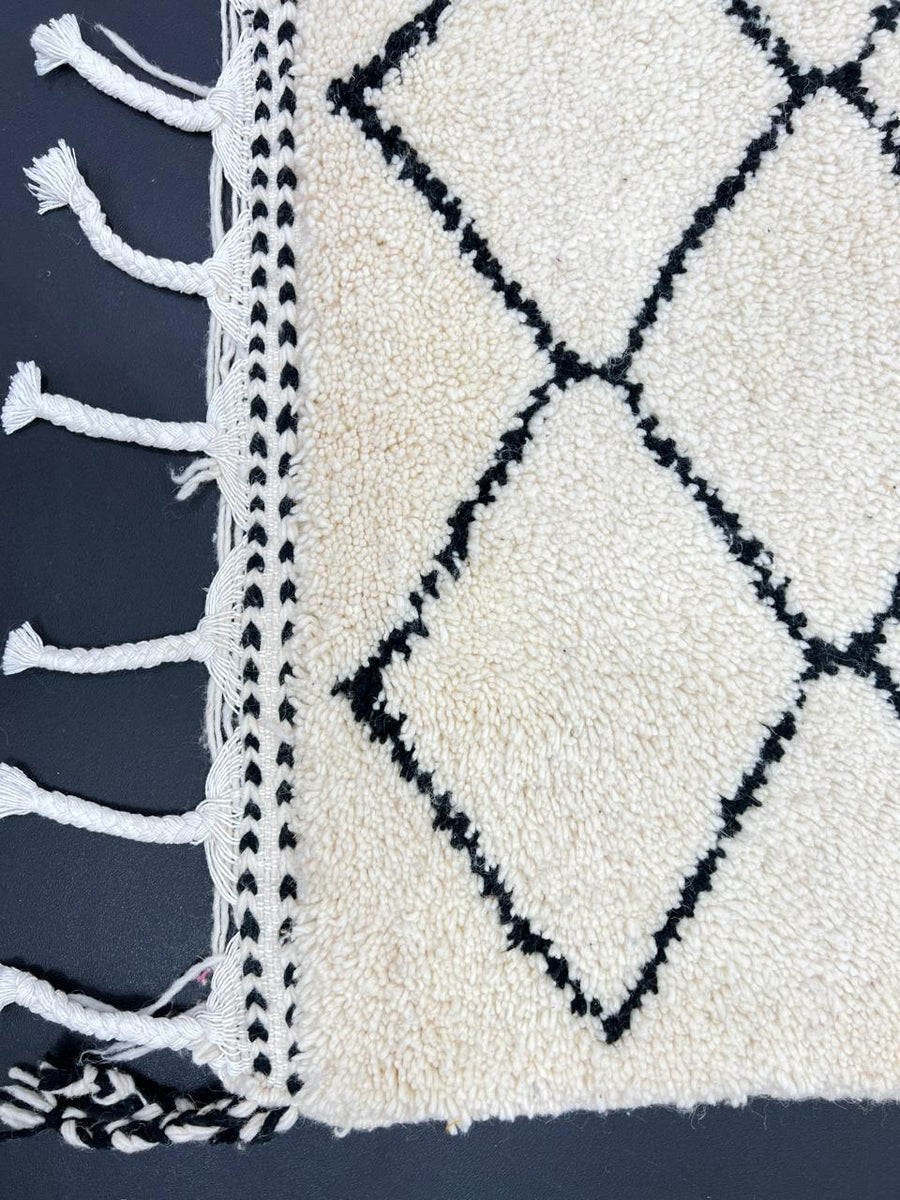 Handmade Moroccan runner rug with classic black diamond lattice design on a white wool background.