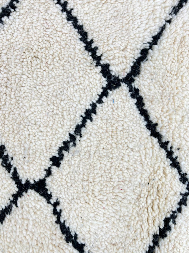 Handmade Moroccan runner rug with classic black diamond lattice design on a white wool background.