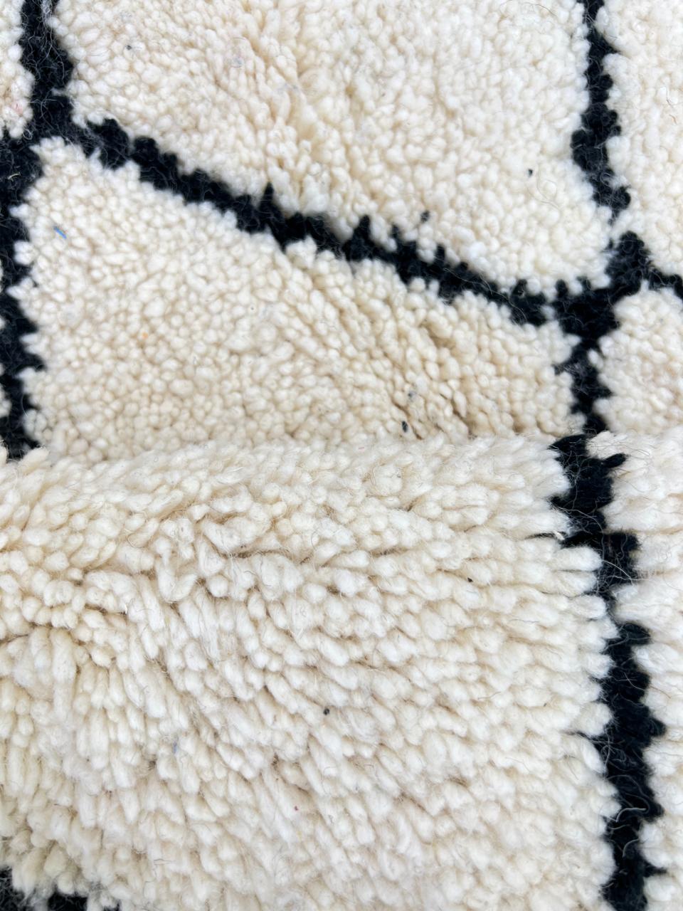 Handmade Moroccan runner rug with classic black diamond lattice design on a white wool background.