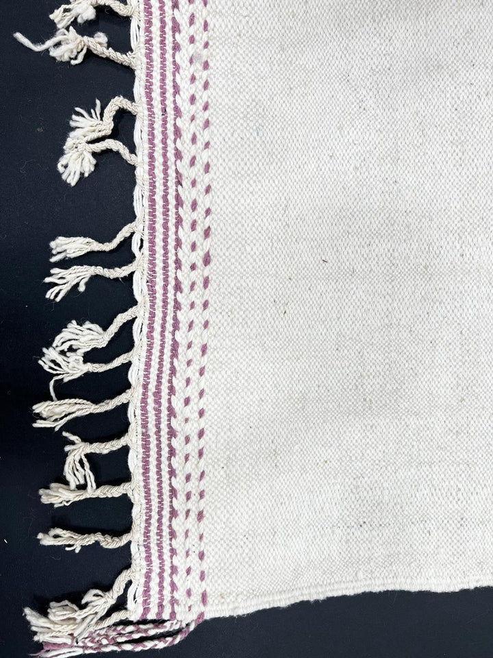 Handwoven Moroccan kilim runner rug with minimalist blush pink and plum geometric pattern on white flatweave wool background.