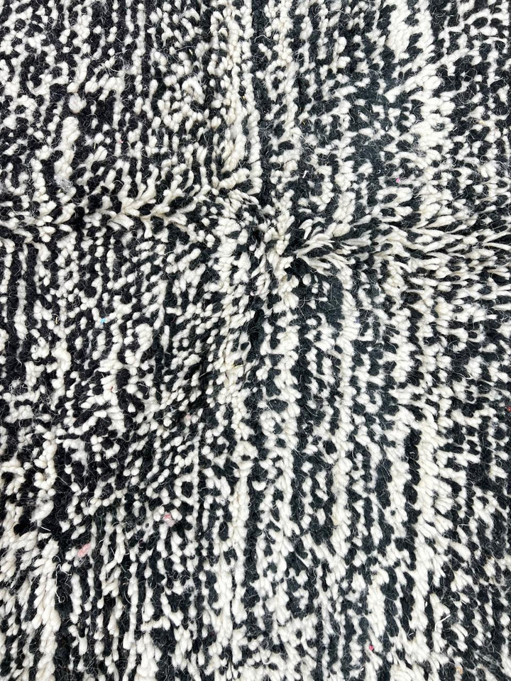 Round Moroccan wool rug with a textured black and white design, showcasing intricate handwoven patterns.