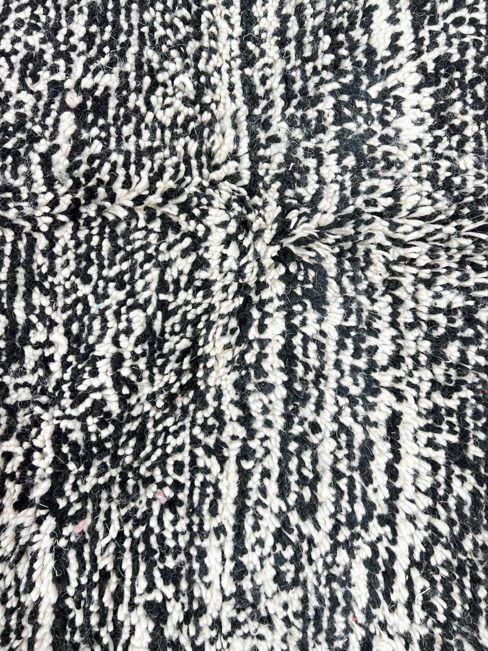 Round Moroccan wool rug with a textured black and white design, showcasing intricate handwoven patterns.