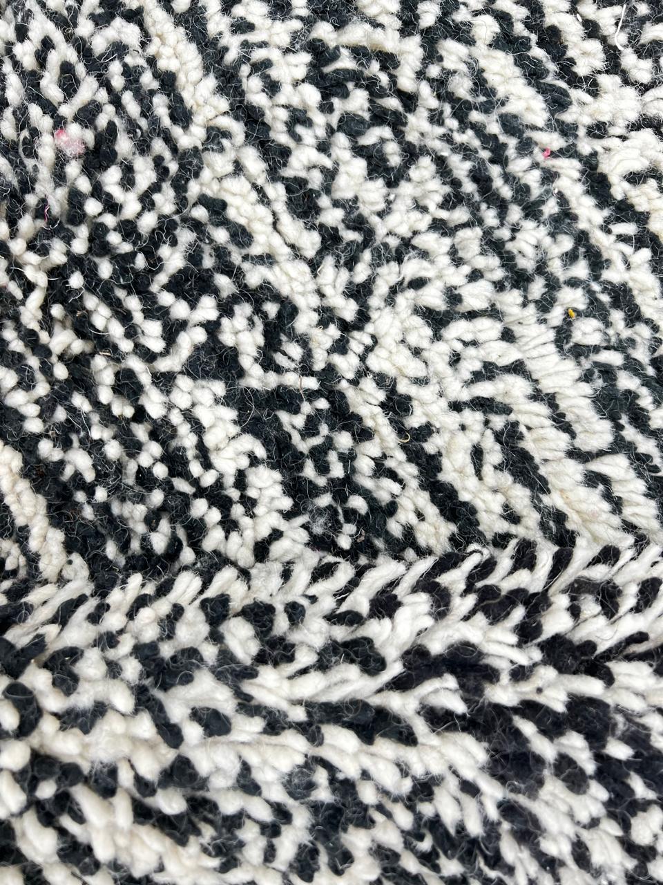 Round Moroccan wool rug with a textured black and white design, showcasing intricate handwoven patterns.