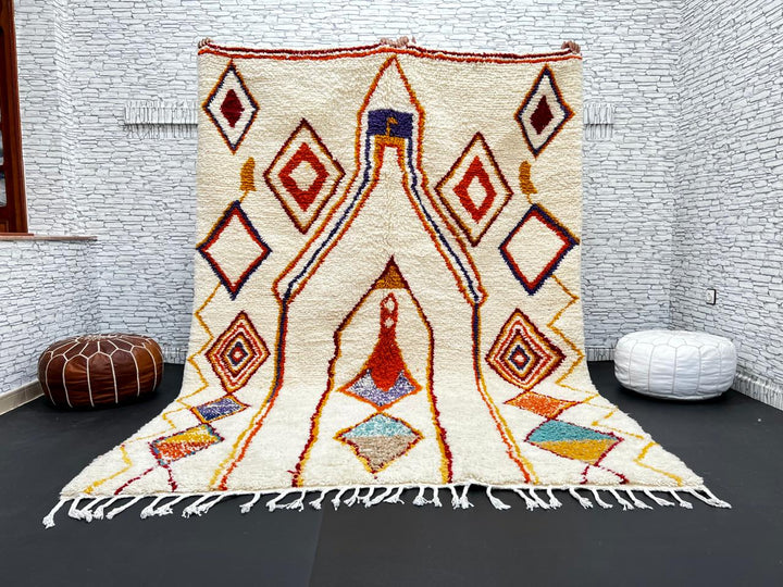 Handwoven Moroccan wool rug with cream background and colorful geometric Berber motifs in orange, yellow, blue, and terracotta