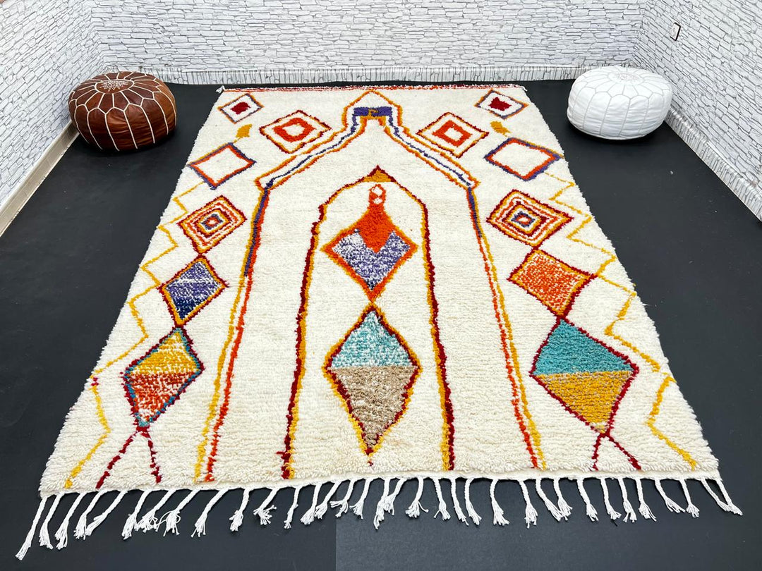 Handwoven Moroccan wool rug with cream background and colorful geometric Berber motifs in orange, yellow, blue, and terracotta