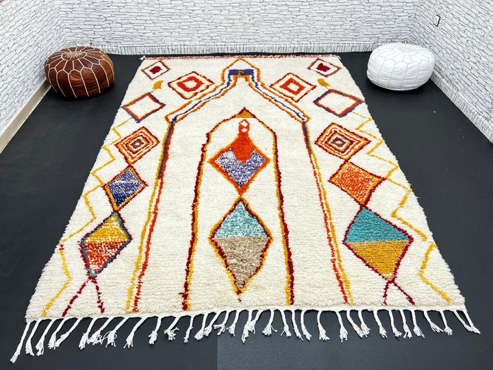 Handwoven Moroccan wool rug with cream background and colorful geometric Berber motifs in orange, yellow, blue, and terracotta