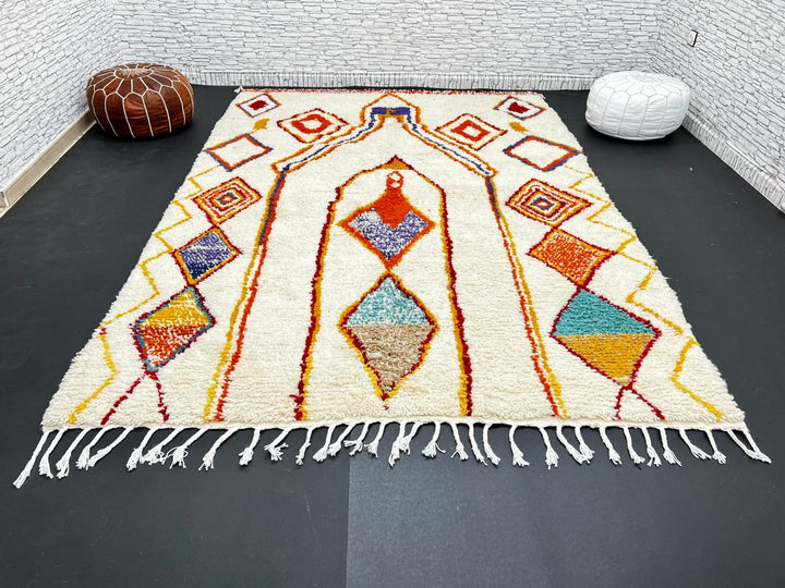 Handwoven Moroccan wool rug with cream background and colorful geometric Berber motifs in orange, yellow, blue, and terracotta